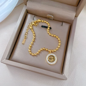 Gold stainless steel beaded bracelet featuring a sparkling interlocking hearts charm