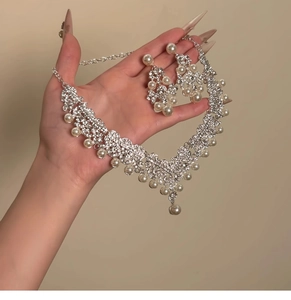 Close-up of elegant V-shaped silver necklace and earring set with pearls and rhinestones