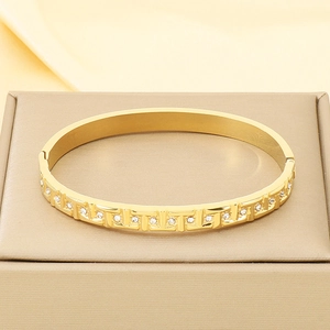 Macro shot of gold-plated geometric bracelet with white crystals and polished finish
