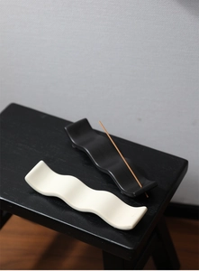 Vue détaillée des supports d'encens en céramique ondulée noir et blanc crème au design épuré
