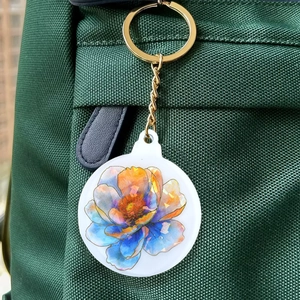 Holografischer runder Acryl-Blumenanhänger mit Goldverschluss am grünen Rucksack