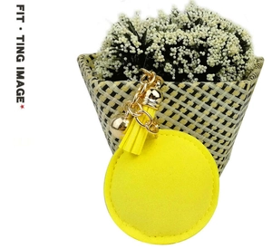 Detail of yellow leather baseball keychain with tassel and gold metal bell accent
