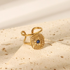 Detailed shot of gold sunburst ring with blue lapis bead on a natural stone surface