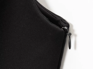 Close-up of invisible teardrop zipper and knit fabric texture on a black camisole top