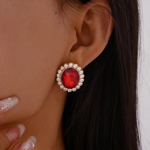Close-up of vintage gold earring with large oval red gemstone and sparkling rhinestones