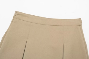 Dettaglio della gonna a pieghe kaki con taglio a vita alta e trama del tessuto twill
