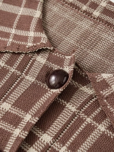 Close-up of brown and beige plaid knit fabric with a glossy dark button detail