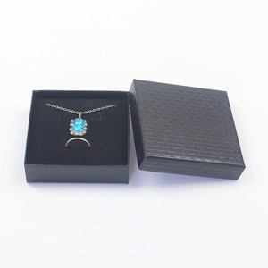 Macro shot of premium black textured jewelry gift box with velvet insert and sapphire pendant