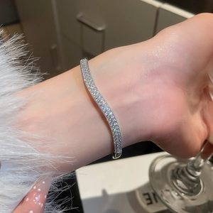Detailed close-up of wavy silver bangle with double rows of sparkling cubic zirconia