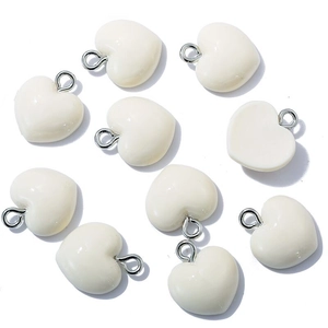 Detailed view of white resin heart-shaped charms with silver metal rings on white base