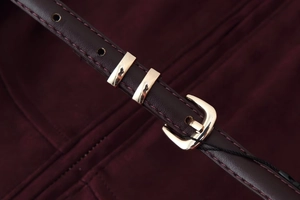 Detailed macro view of dark burgundy faux leather strap with polished gold metal buckle
