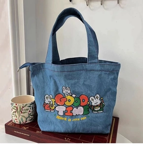 Detail of embroidered cartoon rabbits and Good Time text on a blue denim tote bag
