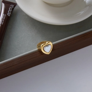 Detail of 18k gold heart-shaped ring with pearl inlay on an elegant jewelry display