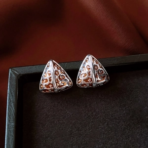 Macro shot of triangle leopard print earrings with silver metal edges on a velvet display