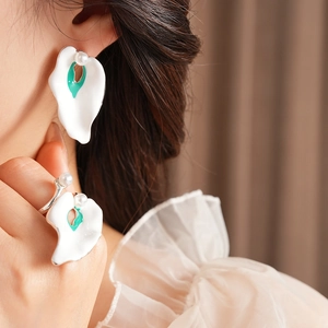 Detail of vintage white petal earrings and ring set with green enamel and pearls