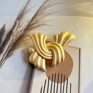 Broche vintage en or mat avec nœud abstrait sur fond décoratif élégant et épuré