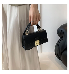 Detail of a vintage black rectangular crossbody bag featuring elegant gold metal buckles