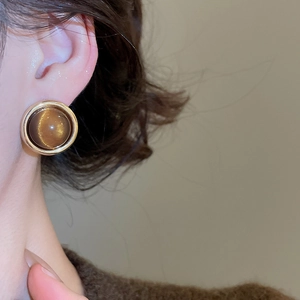 Close-up of 18k gold plated round stud earring with brown tiger eye stone on model