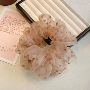 Détail macro du chouchou en tulle beige avec motifs cœurs velours et texture douce