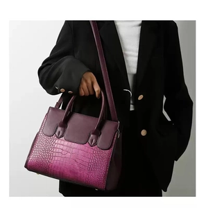 Detail of purple gradient shoulder bag with crocodile texture on model in black suit