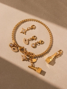 Kreative Flachlage des goldenen Edelstahl-Armbands mit Zirkonia-Anhängern und Charms-Set