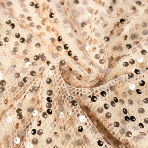 Détail de paillettes dorées scintillantes cousues sur un tissu en maille pour une robe