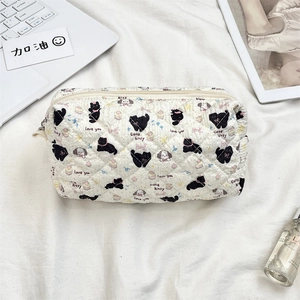 Flat lay of a beige quilted cosmetic bag with cute cartoon motifs and metal zipper detail