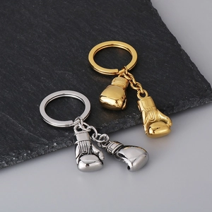 Detailed view of polished gold and silver boxing glove keychains on a natural stone surface