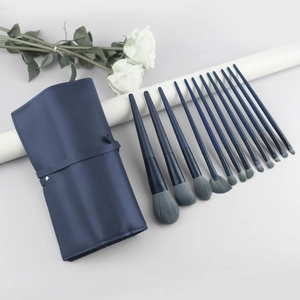 Detailed view of 13 blue makeup brushes with a matching leather roll-up storage bag