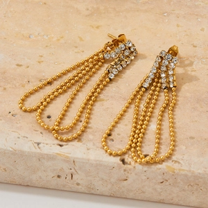 Elegant gold long tassel earrings with sparkling crystals on a natural stone surface