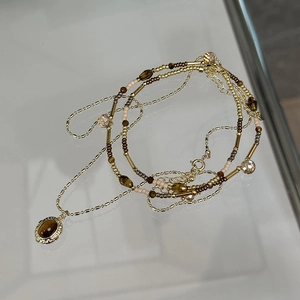 Gold-plated layered necklace featuring tiger eye oval pendant and bead chain details
