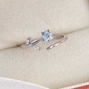 Detailed close-up of silver flower ring with light blue petals and zircon accents