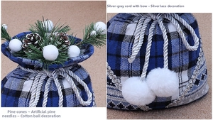Close-up of blue plaid Christmas gift bag with pine cones and white pompom decorations