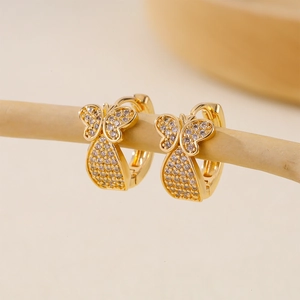 Detailed view of gold butterfly hoop earrings with pavé cubic zirconia on soft background