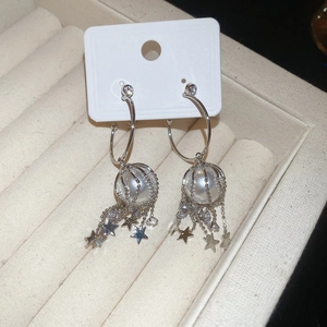 Detail of silver star and pearl tassel earrings with zircons on a white display card