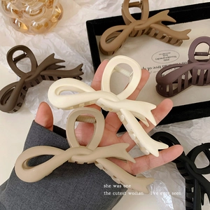 Detail of matte acrylic bow hair claws in gradient earth tones including beige and brown