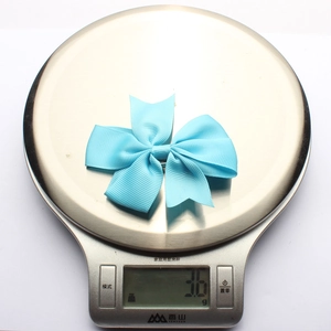 Detail shot showing the lightweight 3.6g blue ribbed ribbon bow hair clip on a scale