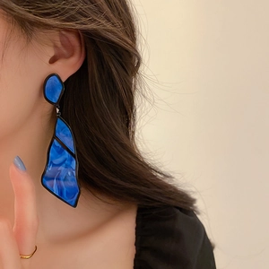 Close-up of blue irregular geometric acrylic drop earring worn by a female model