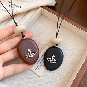 Detail of wooden Saturn orbit pendant necklaces with silver planet logo and cream beads