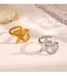 Detailed close-up of gold and silver starfish rings on stone and glass props