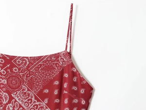 Detail of red paisley print fabric with thin straps and intricate floral textures