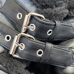 Detail der schwarzen Lederjacke mit Narbenleder, Metallschnallen und warmem Pelzfutter