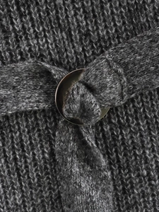 Dettaglio del tessuto a maglia grigio con una fibbia rotonda in metallo sulla cintura