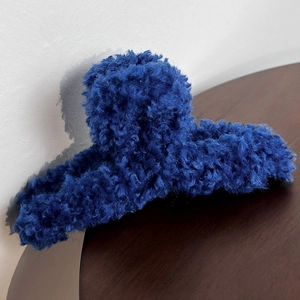Macro detail of the plush dark blue faux lamb hair texture on a French claw clip
