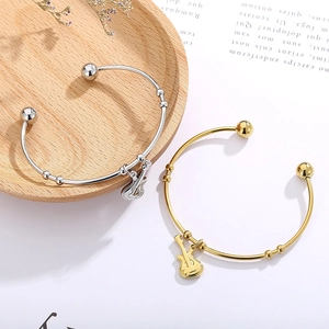 Detail view of open musical instrument bracelets with guitar charms in gold and silver finish