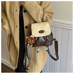 Detail of vintage patchwork backpack in brown PU leather with plush doll pendant