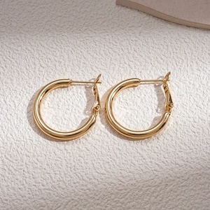 Close-up of golden C-shaped hoop earrings with a smooth polished metallic finish