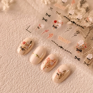 3D bronzing nail stickers with floral patterns, gold hearts and black bows on white base