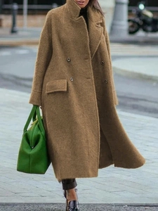 Detail of a brown wool coat featuring oversized lapels and a classic double-breasted closure