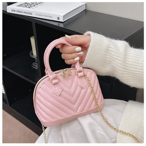 Detail of pink jelly bag with V-shaped texture, gold zipper, and elegant chain strap